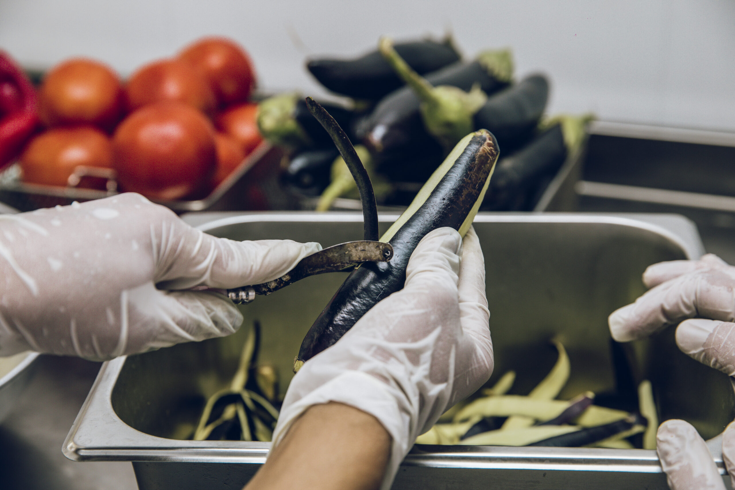 Mains gantées qui épluchent une courgette Mains gantées qui épluchent une courgette